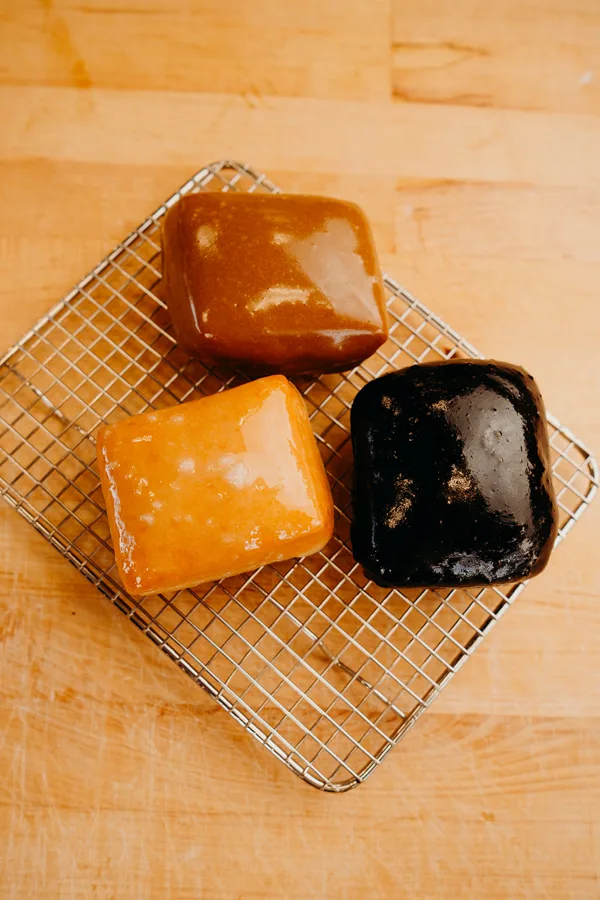 Three glazed Thirst beignets on a cooling rack