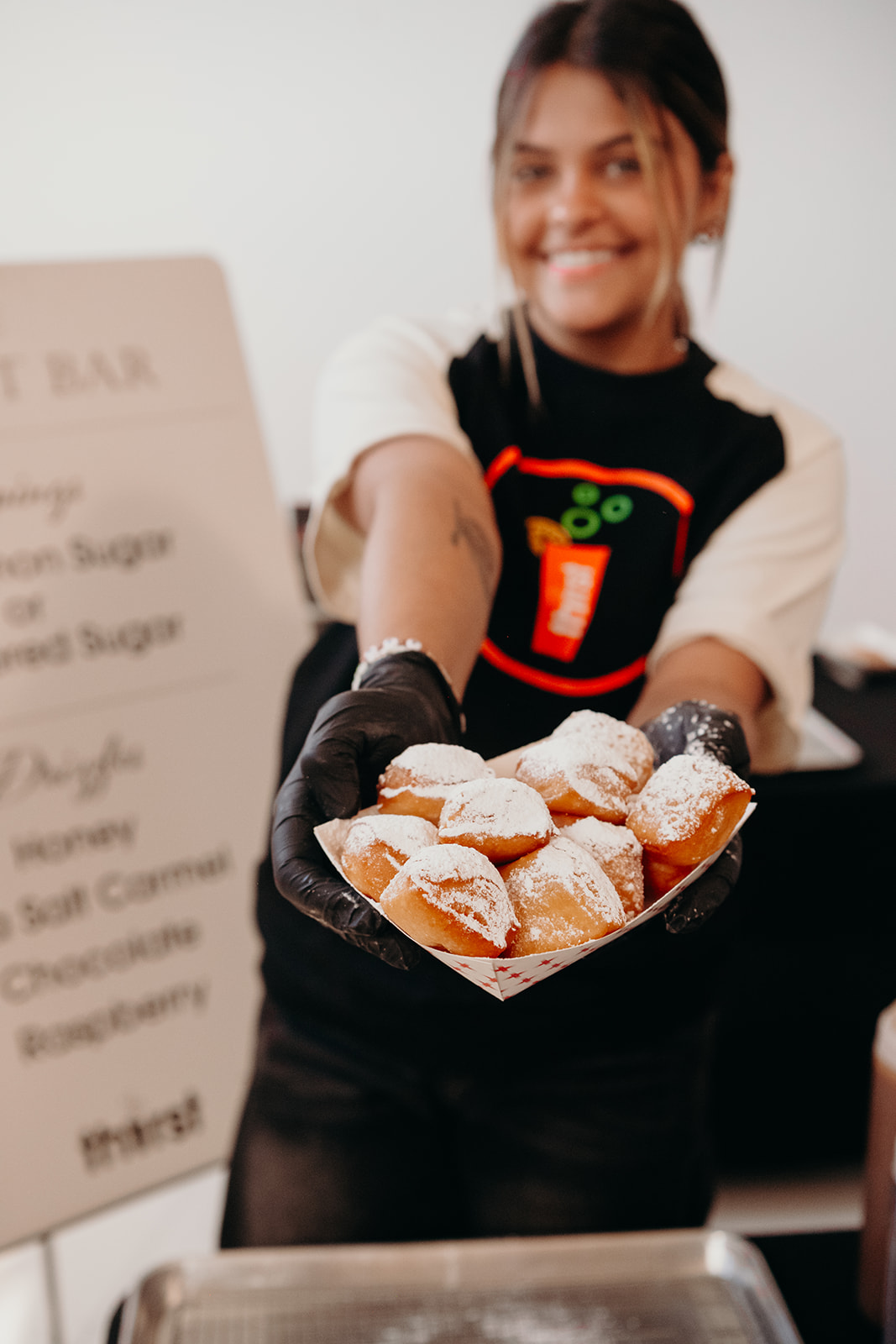 A Thirst team member serving a tray of powdered sugar beignets