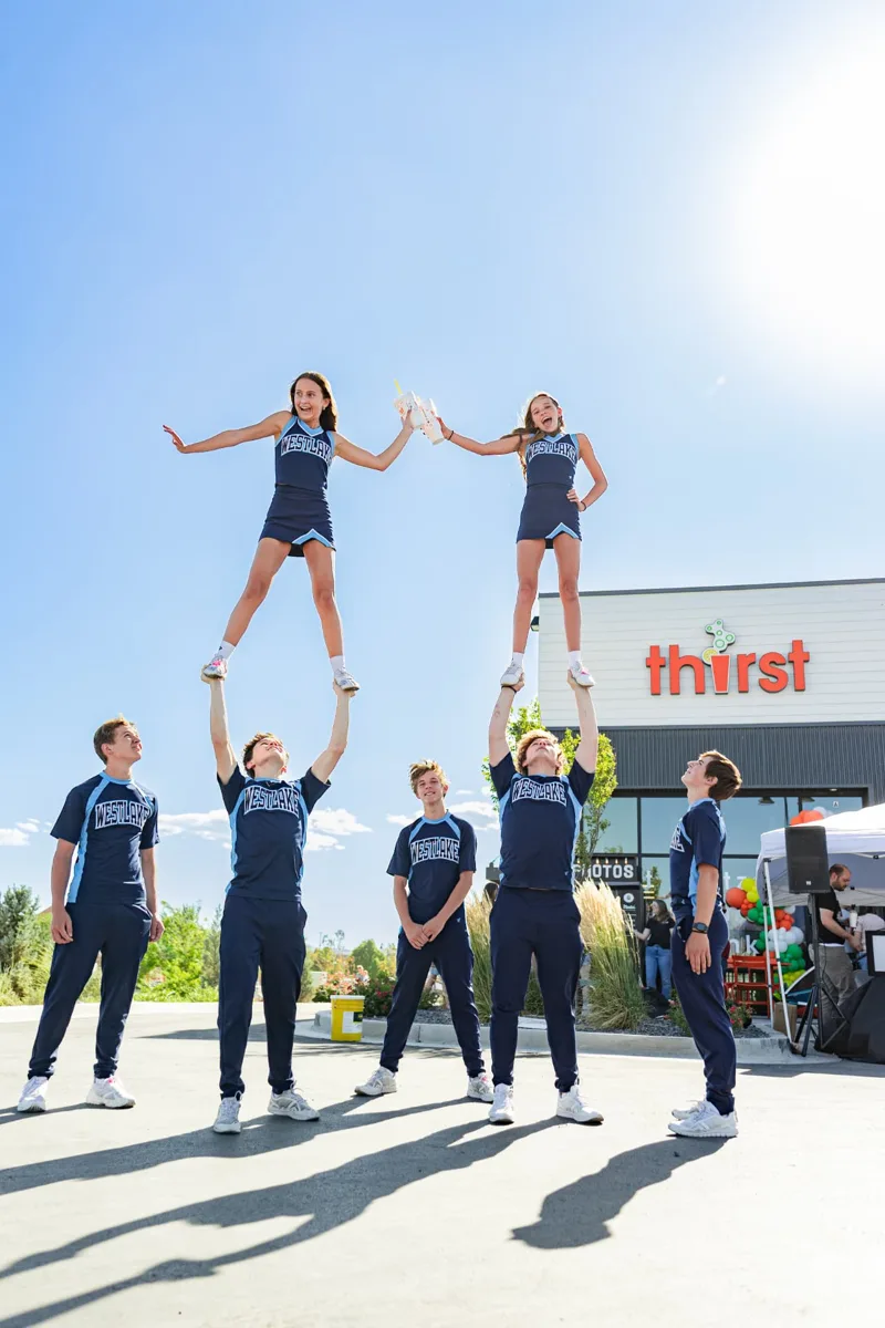 Local cheerleaders celebrating with Thirst drinks at a store grand opening