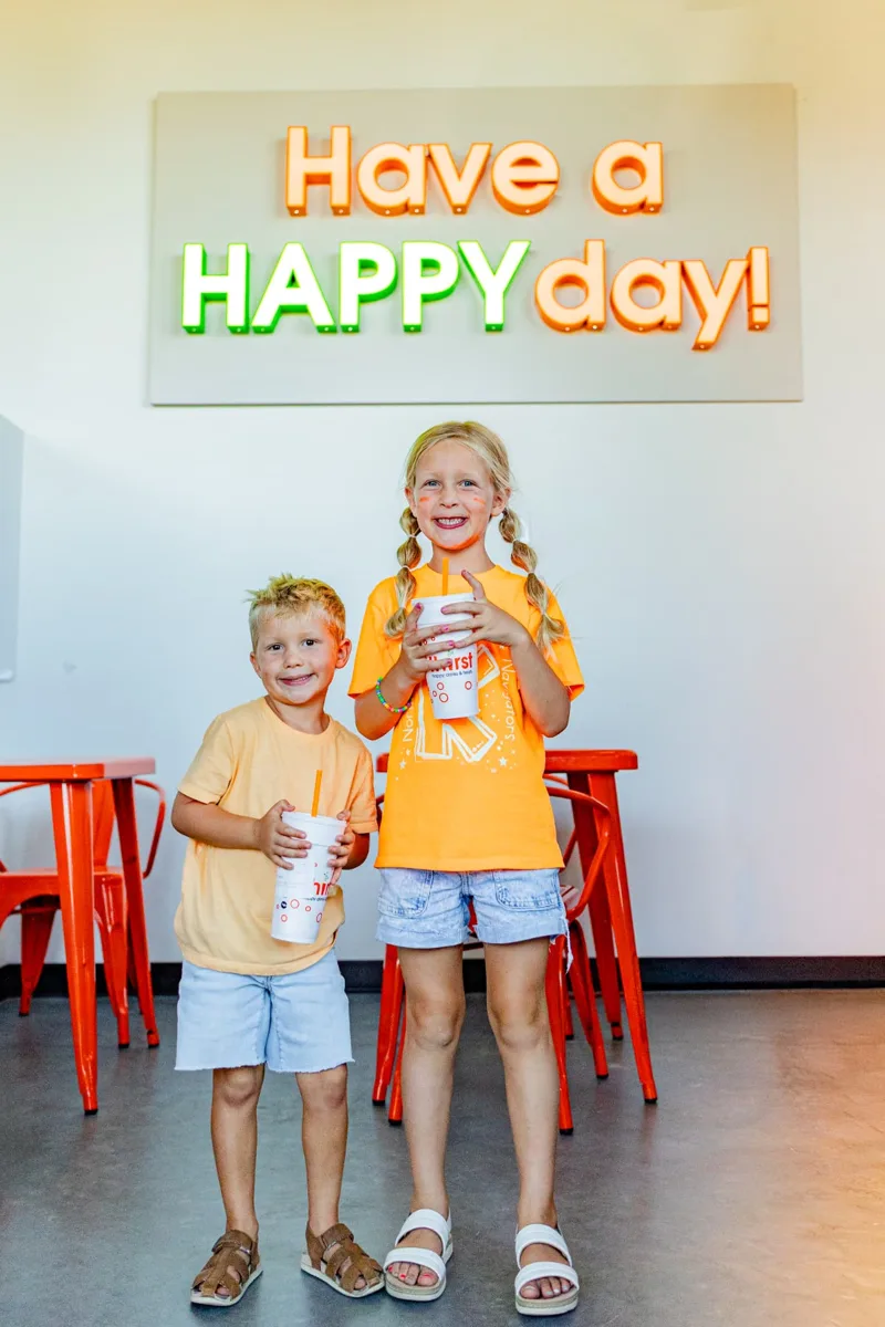 Kids with Thirst drinks under the Have a HAPPY day sign