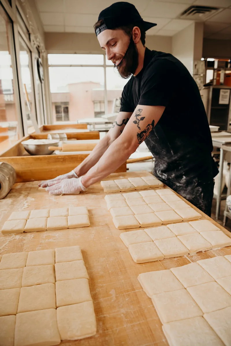 Thirst baker cutting fresh beignet dough at the bakery
