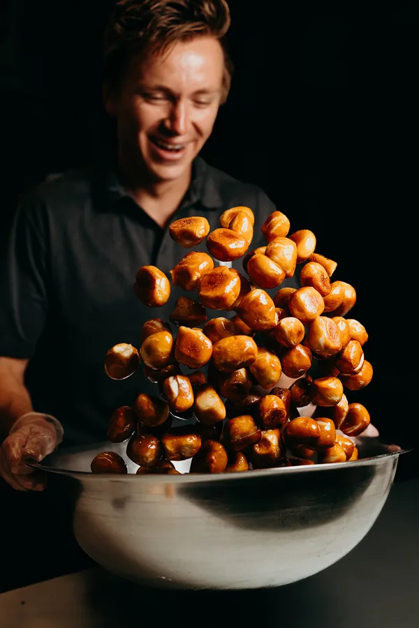 Thirst team member tossing fresh pretzel bites in a big bowl